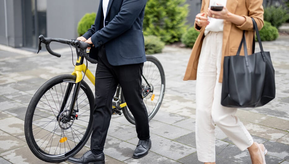 Asian businessman and caucasian businesswoman walking, drinking coffee and talking in city. Concept of business cooperation. Man with bicycle. cropped image with no face